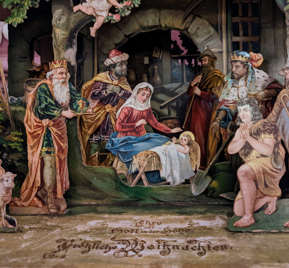 Blick in eine Papierkrippe mit Maria, dem Christkind und den Hirten, um 1900.