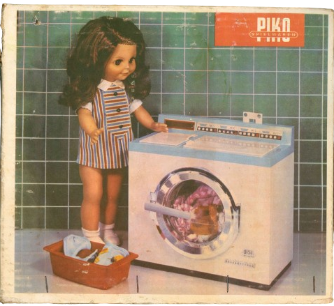 Verpackung der Kinderwaschmaschine PIKO. Abgebildet ist eine Kinderpuppe, die vor der Waschmaschine steht.